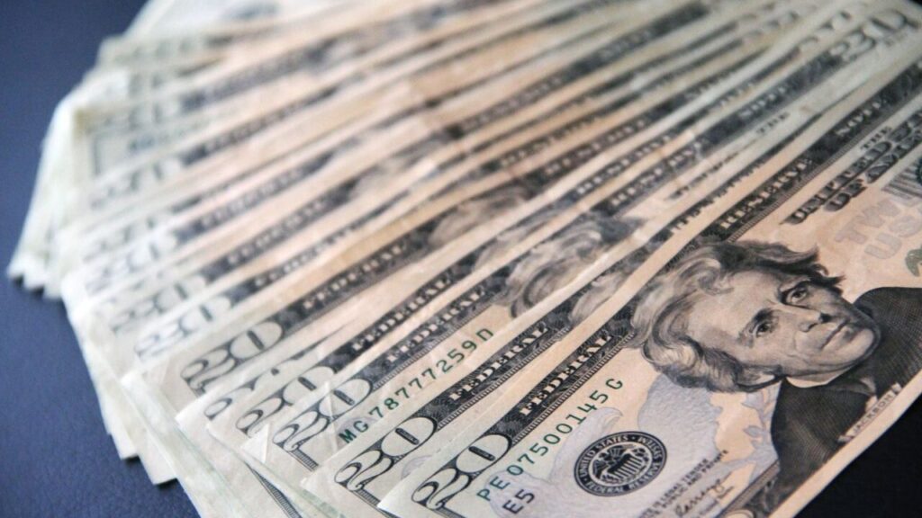 Close-up shot of multiple US twenty dollar bills spread out, symbolizing wealth and finance.
